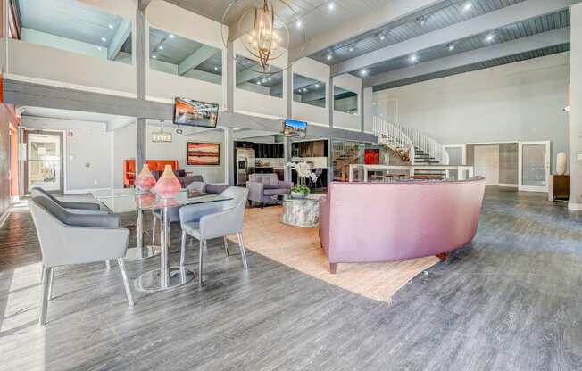 A modern living room with a pink sofa and grey chairs.