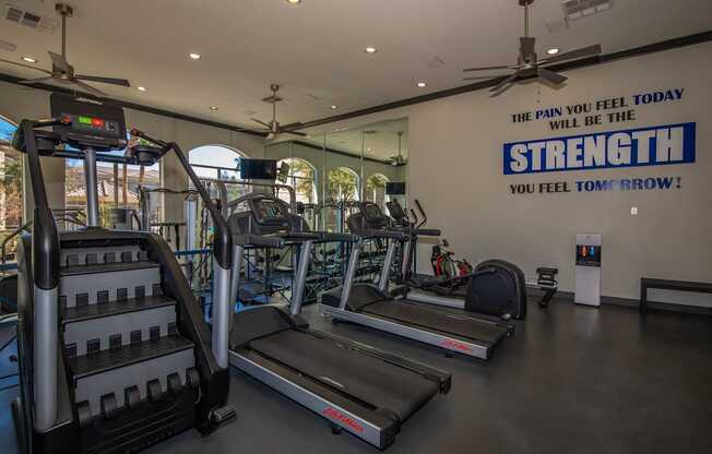 A gym with treadmills and a sign that says "The pain you feel today will be the strength you feel tomorrow!"