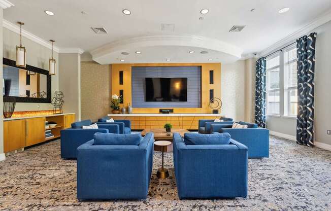 A living room with a large screen television and blue chairs.