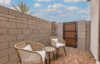 a patio with two chairs and a table next to a brick wall at Village of Chandler Apartments, Chandler, AZ, 85249