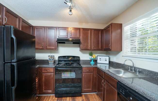 a kitchen with black appliances and wooden cabinets at Radbourne Lake Apartments, North Carolina, 28269