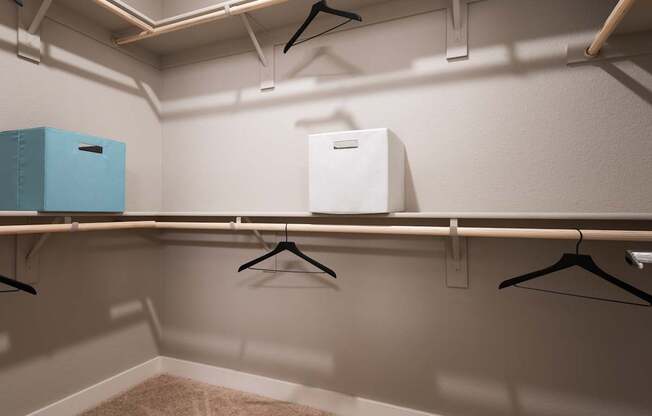 A white box is on a shelf with a blue box and three hangers.