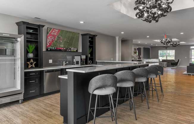 A modern kitchen with a large island and grey bar stools.