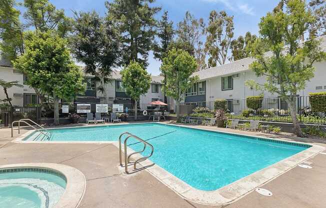 A swimming pool surrounded by trees and a building in the background.