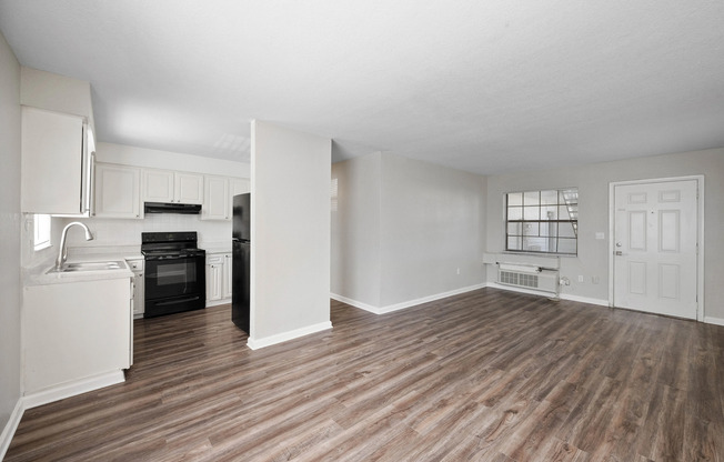 Bright open-concept living space with modern kitchen, featuring sleek appliances and elegant hardwood flooring.