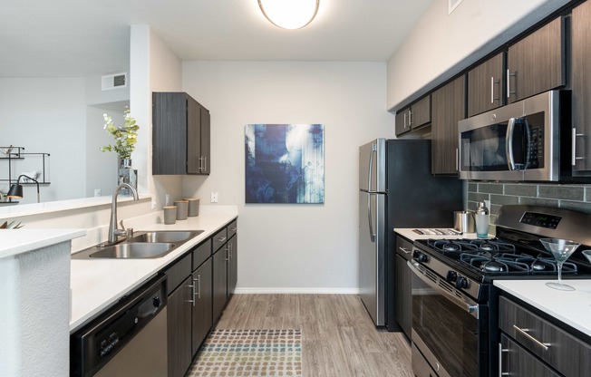 an empty kitchen with stainless steel appliances and wood flooring