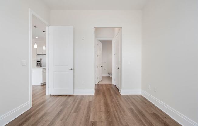 a bedroom with hardwood floors and white walls