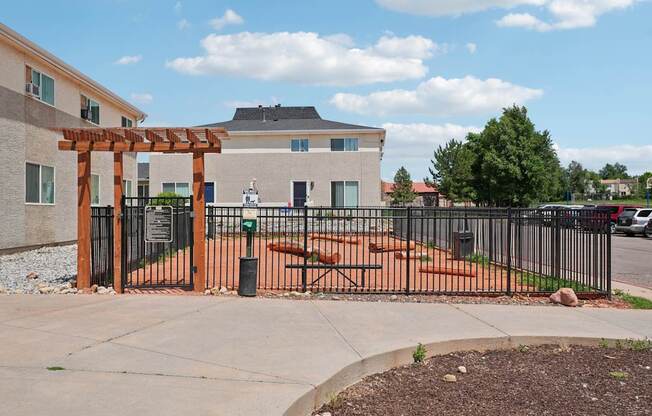 A building with a black gate and a wooden archway in front.