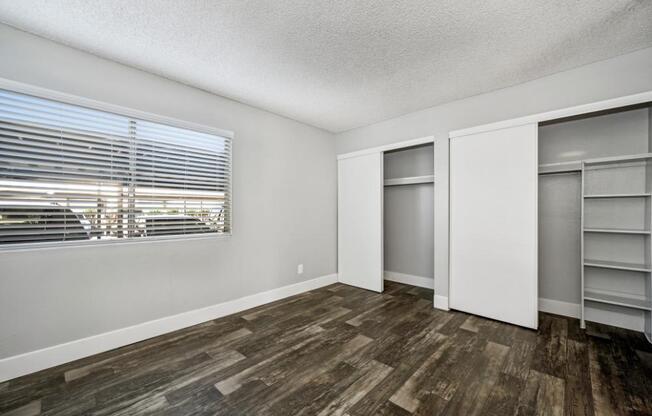 Model bedroom with a window and a wooden floor.