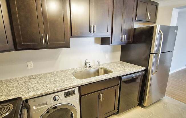 A kitchen with a black refrigerator and a sink.