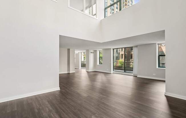 A spacious room with wooden floors and large windows.