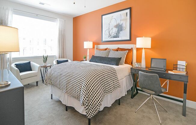 a bedroom with an orange accent wall and a black and white bed