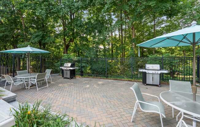 A patio with a table and chairs and a grill.