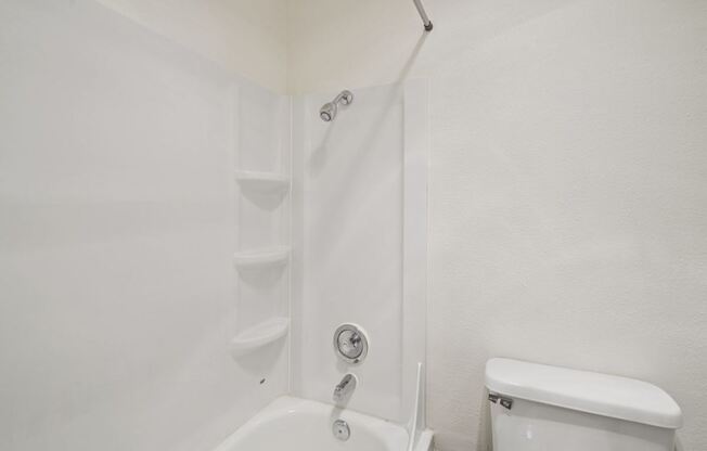 A white bathroom with a toilet and a bathtub.