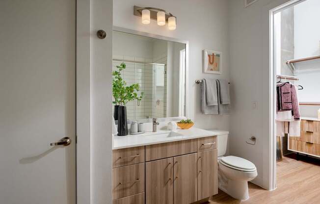 A bathroom with a white toilet and a wooden vanity.