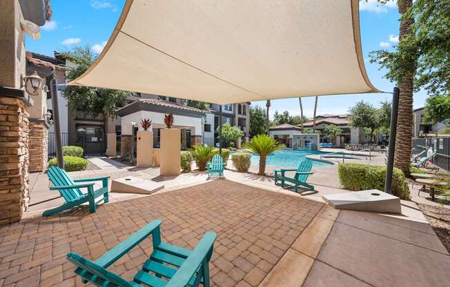 A patio with a white umbrella and blue chairs.
