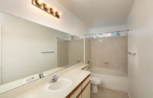 Bathroom with Large Vanity Mirror, Bulb Lights, and Tile Shower Backsplash at Laurel Creek, Fairfield, California