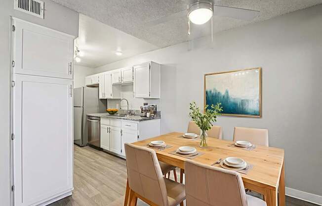 A dining room with a table set for two and a painting on the wall.