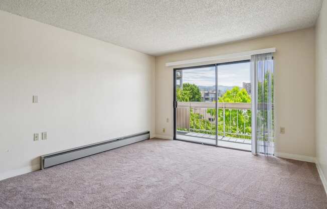 the living room of an apartment with a balcony and carpeted flooring