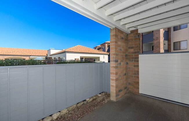 A white fence with a brick pillar in front of a garage.