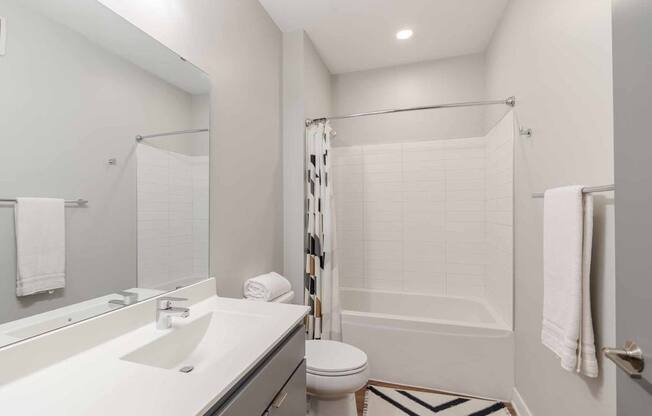A white bathroom with a toilet, sink, and shower.