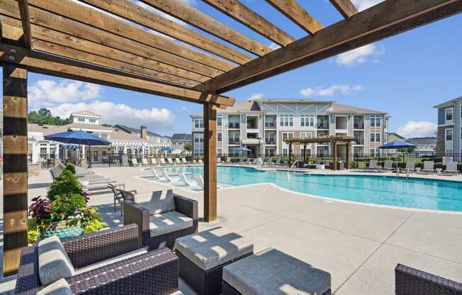 a large swimming pool with lounge chairs and a wooden pergola