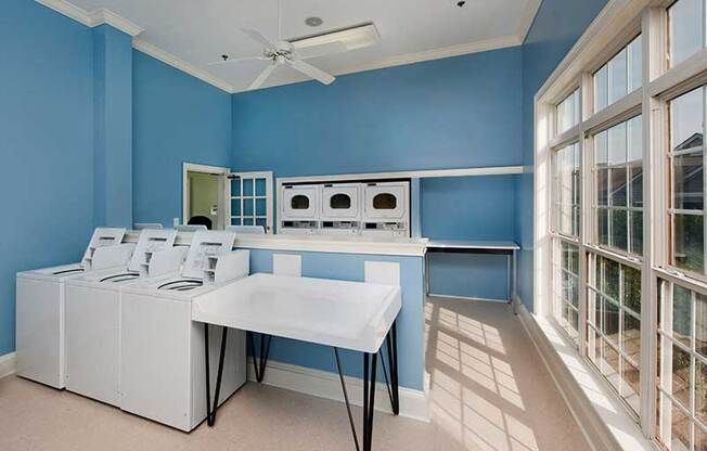 a blue kitchen with a long table and white appliances