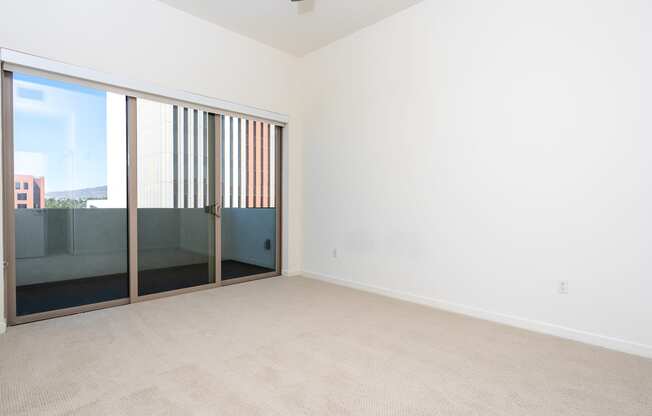 an empty living room with sliding glass doors to a balcony.
