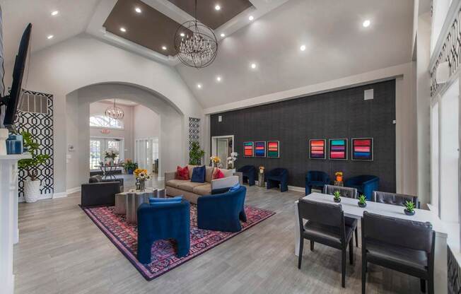 A spacious living room with a blue rug and a dining table set up.