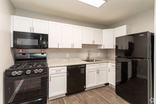 an empty kitchen with black appliances and white cabinets