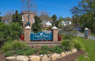 a sign that says aspen run with a building in the background