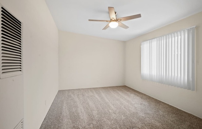 a bedroom with white walls and a white ceiling fan