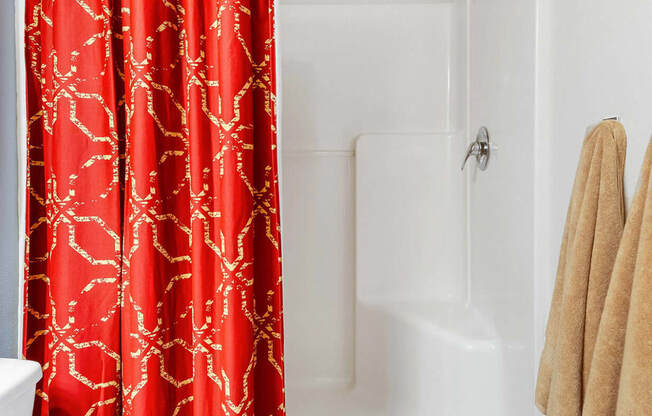 a bathroom with a red shower curtain and a white bathtub at Mullan Reserve Apartments, Montana, 59808