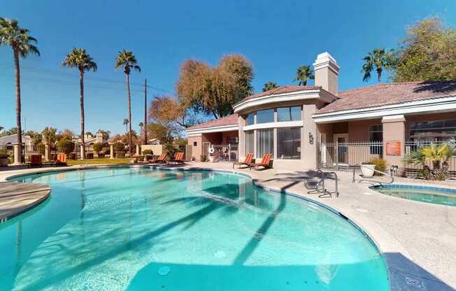 A resort-inspired swimming pool here at Dobson Towne Center featuring sparkling blue water, a relaxing spa, and a spacious sun deck lined with lounge chairs. Surrounded by palm trees and beautifully maintained landscaping, the pool area offers inviting seating and a welcoming clubhouse backdrop, creating the perfect setting to unwind, soak up the sun, and enjoy Arizona living.