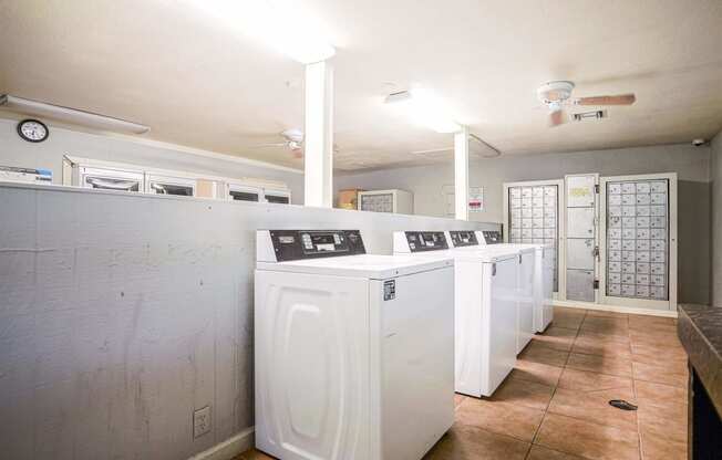 a row of washers and dryers in an empty laundry room