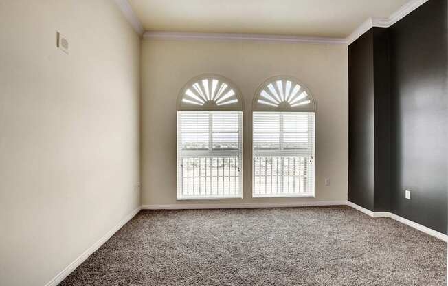 A room with a carpeted floor and a window with blinds.