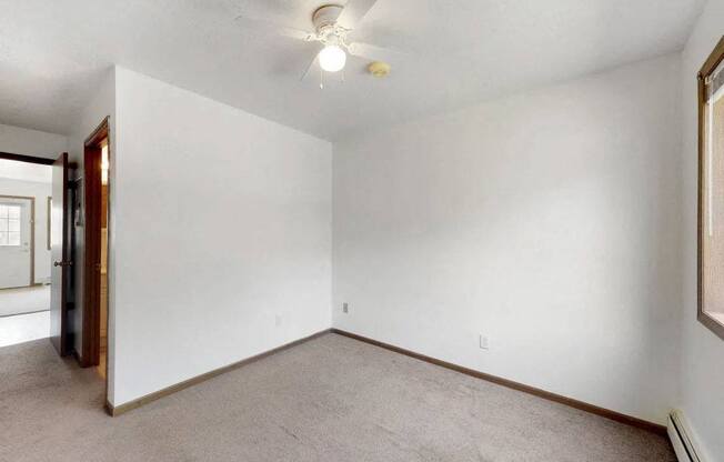 an empty living room with white walls and a ceiling fan