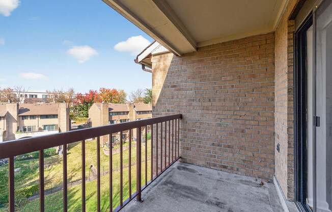 A balcony with a brick wall and a metal railing.