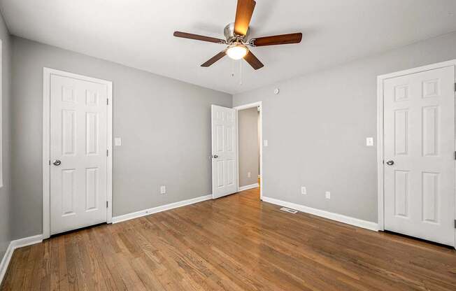 A room with a ceiling fan and wooden floors.