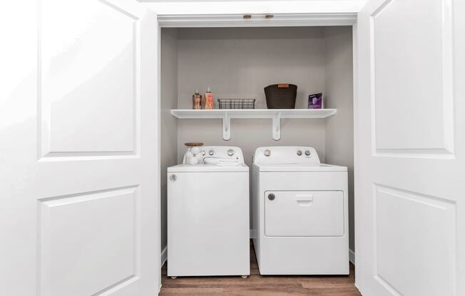 a small laundry room with a washer and dryer and a shelf above it