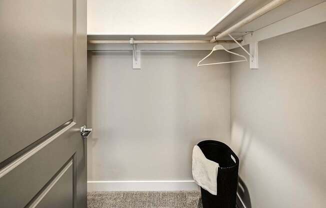 A small room with a door, a hanger and a chair.