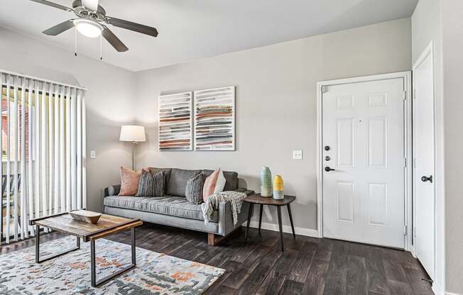 A living room with a grey couch, a coffee table, and a ceiling fan.