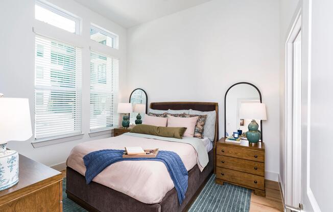 Primary bedroom with tall windows, and warm wood flooring, creating a bright and comfortable retreat.