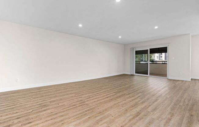 an empty living room with wood flooring and a sliding glass door