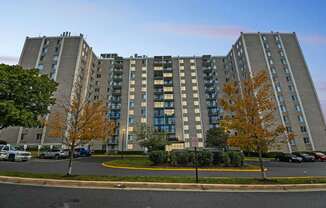A large apartment building with a parking lot in front.
