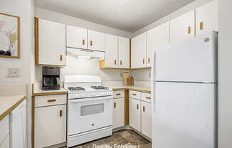 A kitchen with white appliances and cabinets at The Highlands Apartments in Elkhart, IN