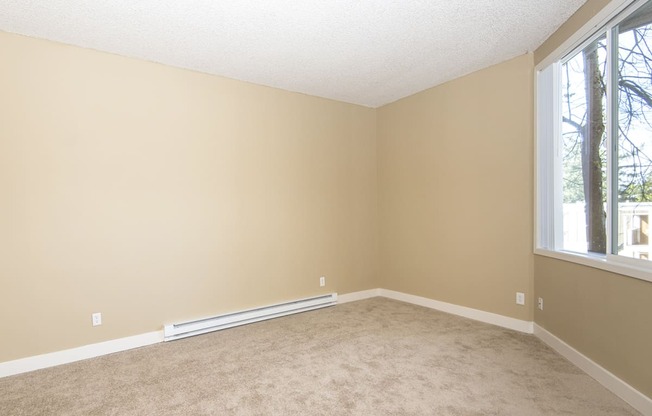 an empty living room with carpet and two windows