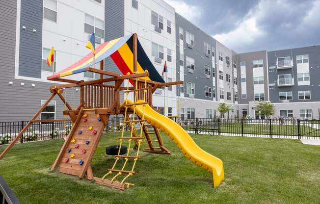 a playground with a swing set and a slide in an apartment building