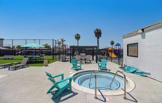A pool area with a hot tub and lounge chairs.