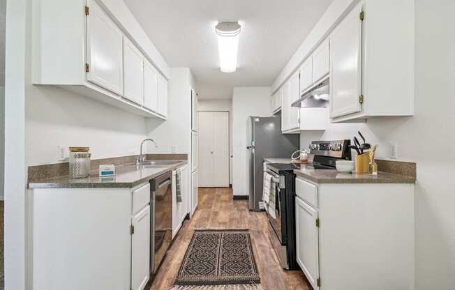 A kitchen with white cabinets and a black refrigerator.
